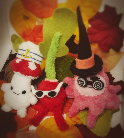 Tiny plush fanart for the video game Ooblets - from left to right: Shrumbo, Radlad, and Clickyclaws, all wearing tiny accessories.